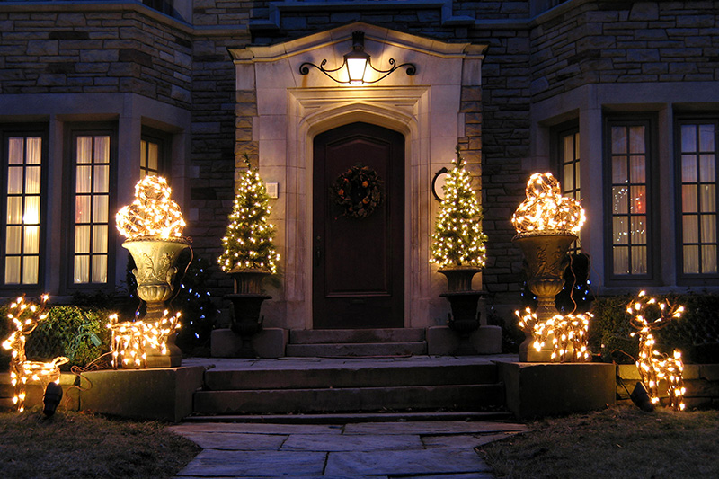 the front porch entry to a home decorated with white lights for Christmas
